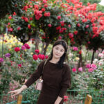 一个站在花里拍照的女人